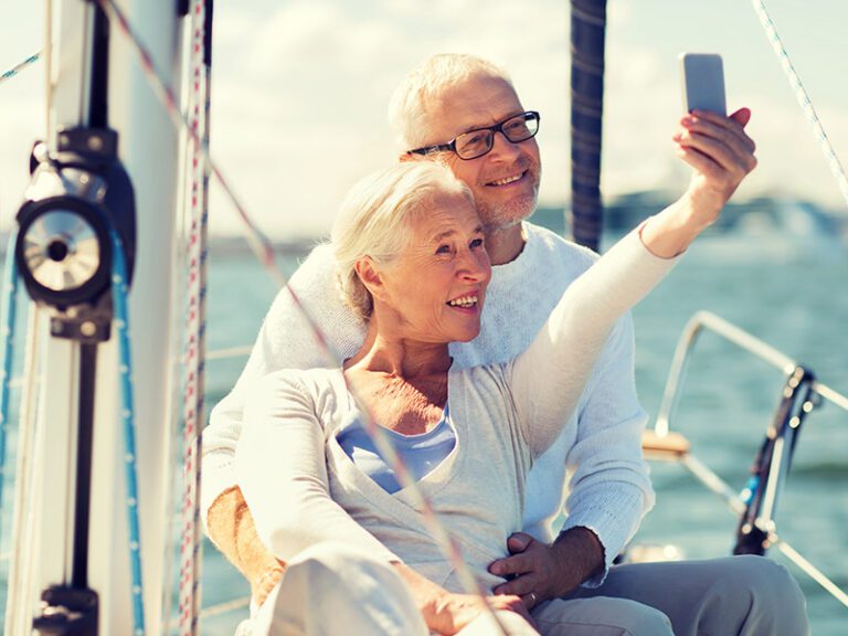 Elderly couple enjoying the seascape on a yacht and capturing memories with selfies