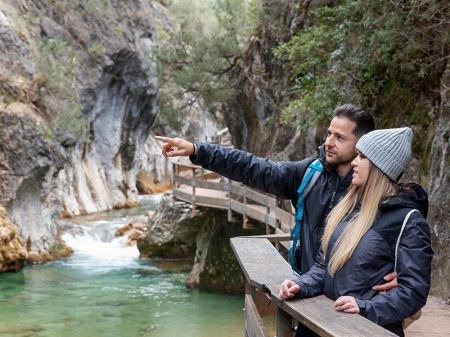 Couple hiking on mountain path with river view